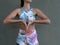 Close up girl in sportswear bring hands in mudra at heart chakra at grey wall at background