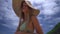 Close-up of a girl in a straw hat on the beach, running her hand from her thigh to the chest, slow shot from bottom