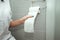 Close-up, girl tears off toilet paper while sitting on the toilet