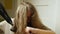 Close-up of a girl using a round comb and an electric hair dryer to dry her long hair. Care and maintenance of hair at