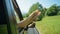 CLOSE UP: Girl wiggling her toes with her legs sticking out the car window.