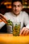 close-up of glass on bar in which hand of male bartender puts green mint leaves.