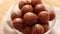 Close up glass bowl with organic Macadamia nuts on table against wood background.