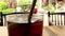 Close up of a glass of cola-colored fizzy drink with Asian tuk tuks passing i