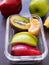 Close-up, Glass container lunch box of mix fruit apple, kiwi, orange and banana on grey background.