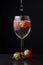 Close-up of glass cup with strawberries, with water falling in splash, two strawberries, on slate, black background,