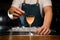 Close-up of glass of drink and hand of bartender which decorate it with berry