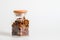 Close up. A glass jar with a wooden lid, contains raisins. White background. Copy space