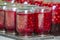 Close-up of glass jars with ripe red juicy sweet cherries covered with metal lids upside down on wooden plate. Homemade preserved