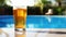 Close up of a glass pint of cold beer near the pool