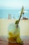 Close up of glass with refreshing lemongrass coctail with mint, lime on sea beach background