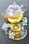 Close-up glass teapot and teacup with green tea and spring flowers