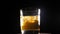 Close-up of a glass of whiskey with ice spinning around on a black background.