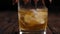 Close-up of a glass of whiskey slowly spinning around on a black background.
