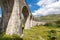 Close up of Glenfinnan Viaduct arched pillars surrounded by mountains during sunny day