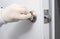 Close-up, a gloved hand checks the correct operation of the front door latch, closing and opening from inside the apartment