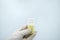 Close-up of gloved hand holding transparent pill bottle on white background