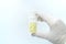 Close-up of gloved hand holding transparent pill bottle on white background