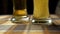 Close-up of goblets with pouring beer on black background