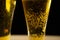 Close-up of goblets with pouring beer on black background
