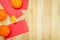 Close up gold ingots, mandarin oranges and red envelope pocket ang pao over brown wood plank table background top view for