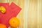 Close up gold ingots, mandarin oranges and red envelope pocket ang pao over brown wood plank table background top view for