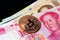 Close-up of a golden bitcoin on face of Chinese yuan banknote. Cryptocurrency or Asia economy business concept.