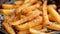 Close up of golden brown french fries frying in the deep fryer, creating crispy texture