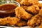 Close-up of golden brown fried chicken tenders with ketchup and honey mustard dipping sauce