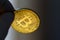 Close up of a golden BTC coin in front of dark background