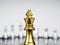 Close-up golden king chess piece standing on battle chessboard in front of many silver chess pieces.