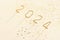 Close-up of golden sparklers in the shape of numbers 2024 and sparkles stars and glitter on beige isolated background. The concept