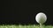 Close up of golf tee and ball on grass and black background, copy space, slow motion