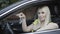 Close-up of gorgeous Caucasian blondie posing on driver`s seat with car keys. Portrait of beautiful blond Caucasian