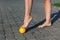 close-up of graceful bare feet of young woman standing on tiptoes on spiked massage ball on paving slabs outdoors