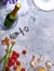 Close-up of a gray table with plate, champagne, tomatoes, asparagus, glasses, corkscrew, flowers on a gray background.