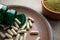 Close up Green capsules, bottle and powder on a clay brown plate