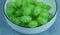 Close-up of green grapes on white porcelain plate in overhead view