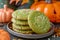 Close up of Green Matcha Cookies with Sesame Seeds on Plate, Festive Halloween Decorations in Background