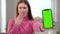 Close-up green screen phone in hand of blurred amazed astonished woman at background. Unrecognizable Caucasian young