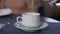 Close-up green tea pouring in white cup in slow motion. Unrecognizable waiter serving client in restaurant indoors