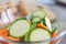 Close up of green zucchini cucumber and carrot slices in a bowl. Healthy food preparation concept