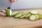 Close up of green zucchini cucumber cutting with a knife. Healthy food preparation concept