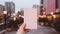 Close-up of a greeting card made of white paper held by a woman against a blurred night city background. Generative AI