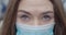 Close-up of grey eyes of young woman in protective mask looking at camera. Portrait of brunette beautiful girl outdoors