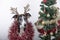 Close-up of greyhound breed dog with reindeer antlers and garlands around the body and Christmas tree. Christmas and New Year 2020