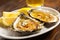 close-up of a grilled oyster with garlic sauce and a lemon wedge