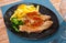 close up of grilled pigs trotter with fried potato and asparagus served on white plate on wooden table