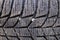 Close-up of grooves on a car tire, stones stuck inside the rubber. Winter wheels after use. Selective focus.