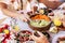 Close up of group of caucasian people take vegetables vegetian food from a table and eat having fun all together at restaurant or
